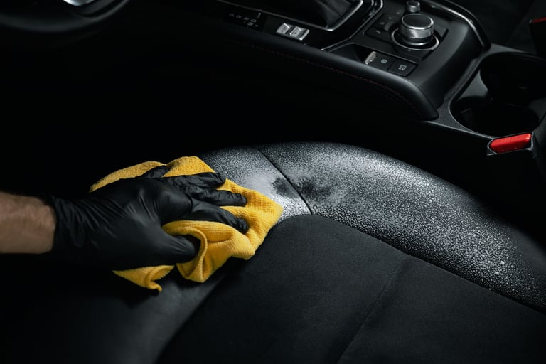 Dieptereiniging van een zwarte lederen autostoel met schuim en microvezeldoek