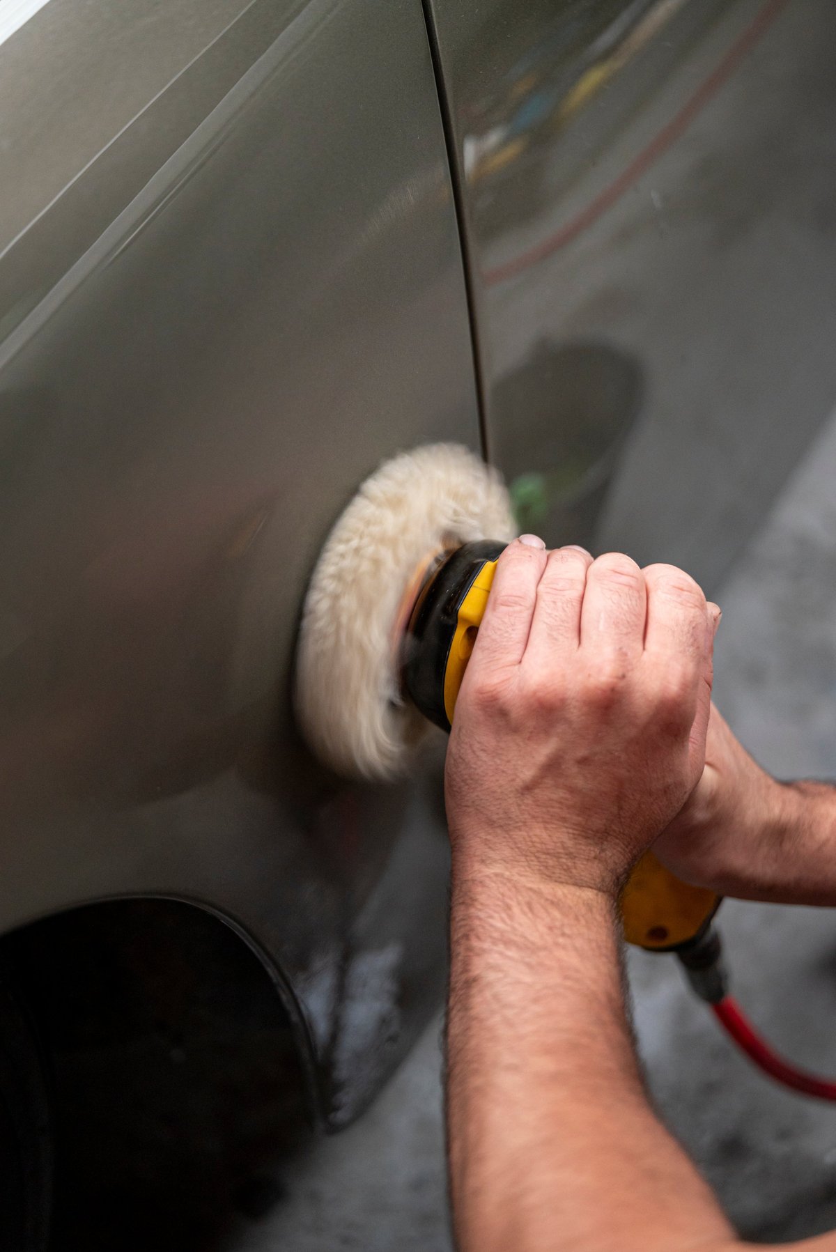 Car waxing and paint restoration process close up with rotary polisher