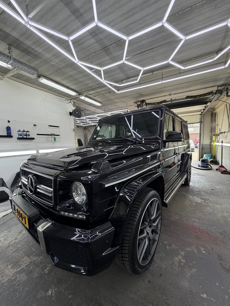 Zwarte Mercedes-Benz G-Class in de garage met hexagonale plafondverlichting