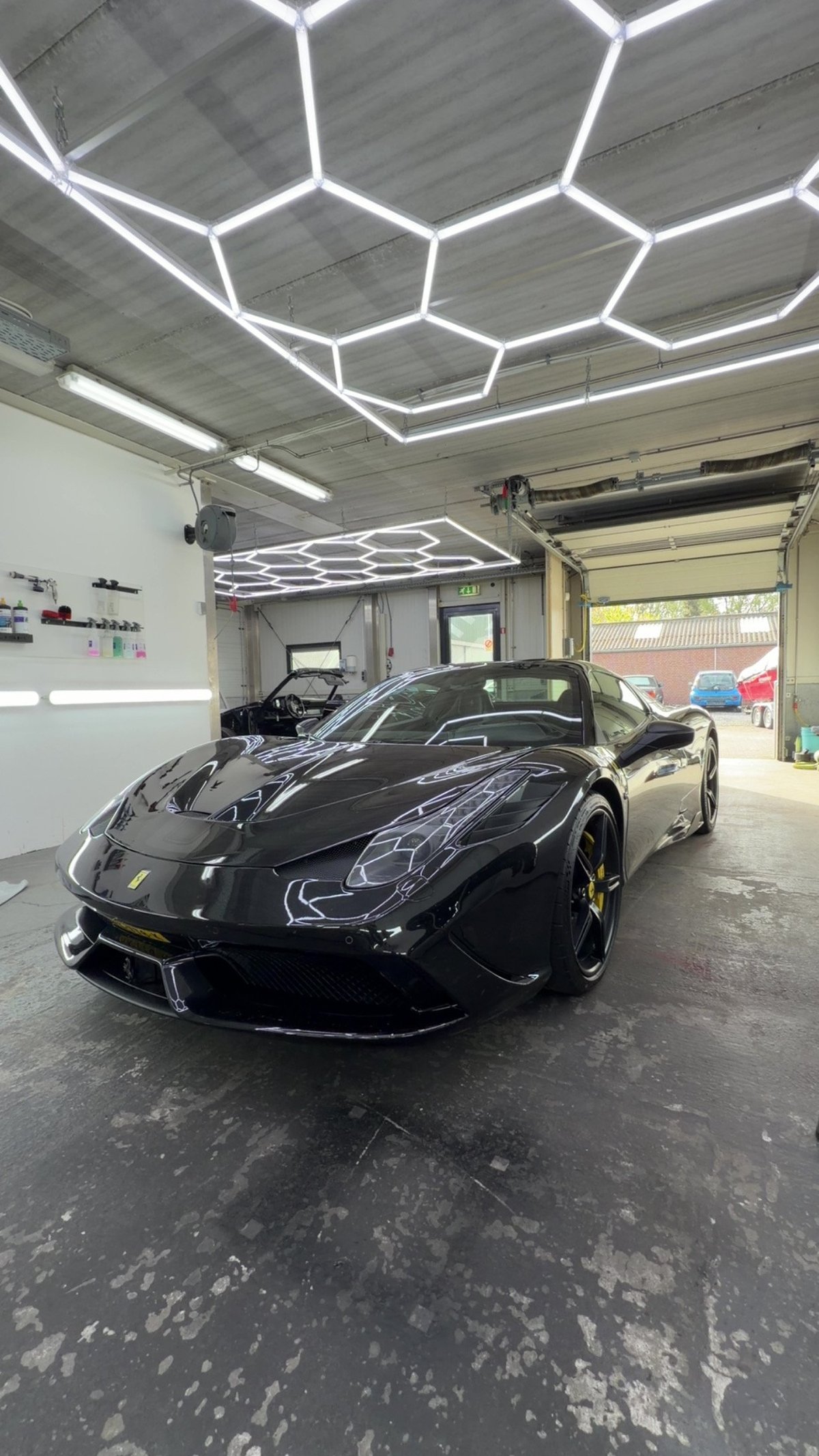 Black sports car in the garage under hexagonal LED lighting