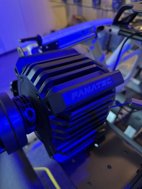 Close-up of a blue Fanatec racing simulator component with heatsink fins and RGB lighting