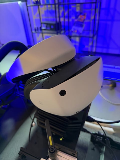 White and black VR headset displayed on a stand with blue lighting